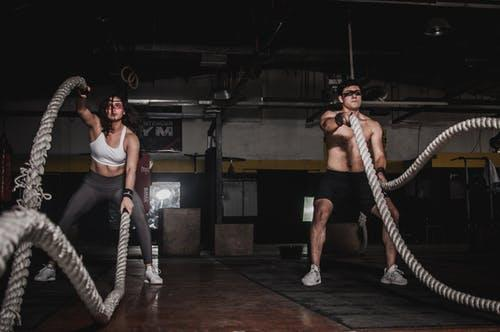 Man and woman working out with industrial ropes